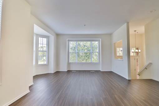 A spacious room with wooden floors and large windows.