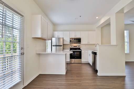 A kitchen with white cabinets and a wooden floor.