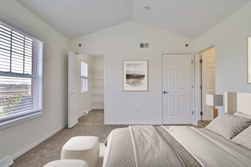 A bedroom with a bed, chair, and picture on the wall.