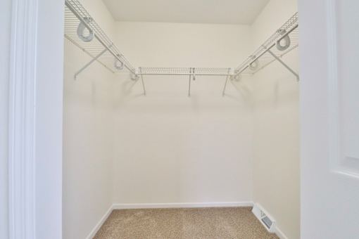 A white closet with a carpeted floor and a white door.