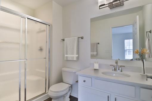 A white bathroom with a toilet, sink, and shower.