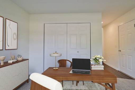 A laptop is on a wooden table with a white chair in front of it.