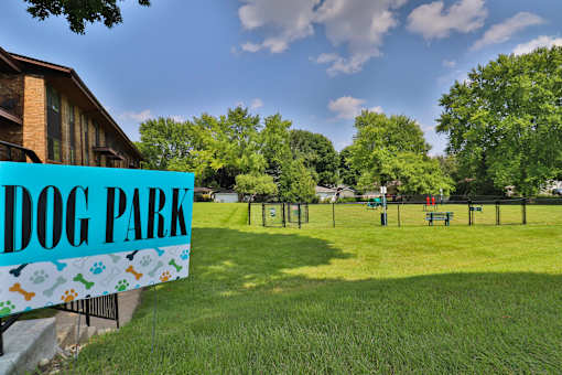 A sign that says Dog Park in front of a green field.