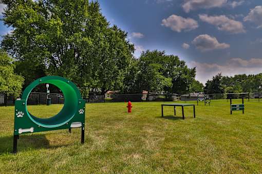 A dog park with a green tunnel and a red fire hydrant.