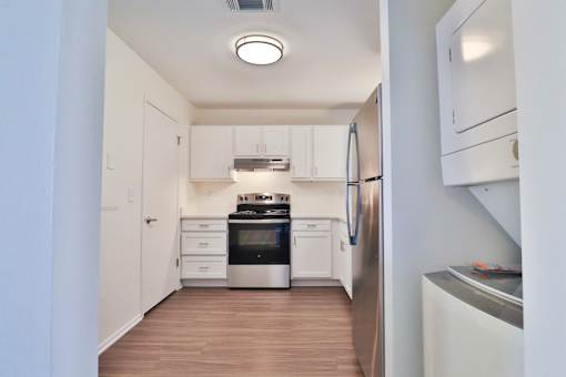 A kitchen with white cabinets and a stainless steel refrigerator.