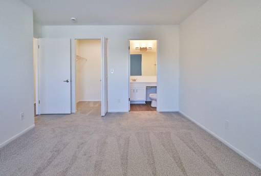 A carpeted room with a desk and a white door.