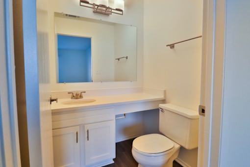 A white bathroom with a toilet, sink, and mirror.