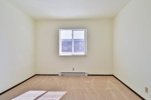 A room with a window and a radiator on the floor.