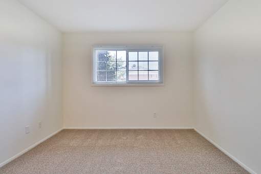 A room with a window and carpeted floor.