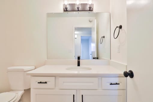 A white bathroom with a sink, toilet, and mirror.