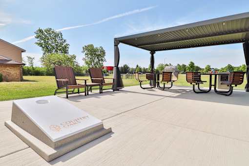 A concrete structure with the word "SALE" written on it is in the foreground of an outdoor seating area with several chairs and tables.