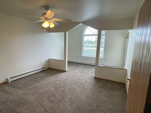 A room with a ceiling fan and carpeted floor.