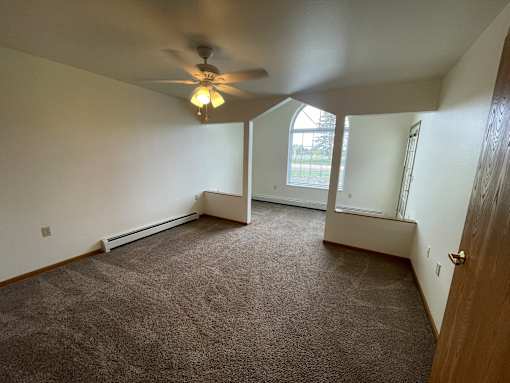A room with a ceiling fan and carpeted floor.