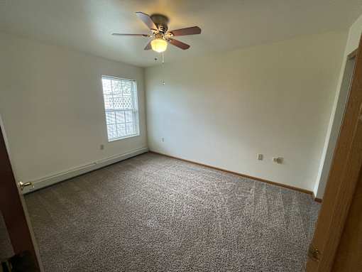 A room with a ceiling fan and carpeted floor.