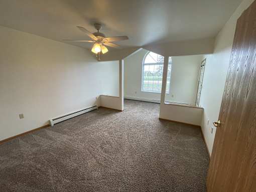 A room with a ceiling fan and carpeted floor.