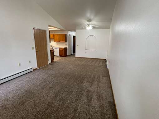 A long hallway with a carpeted floor and a ceiling fan.