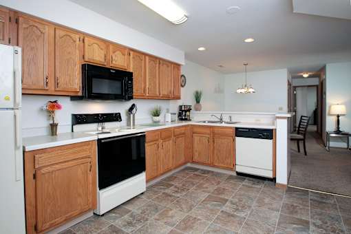 A kitchen with wooden cabinets and a black microwave above the stove.