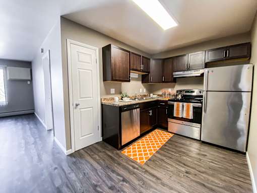 A kitchen with a refrigerator, oven, and sink.