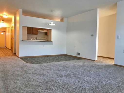 A spacious living room with a kitchenette in the background.