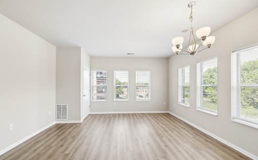 A large, empty room with wooden floors and a chandelier.