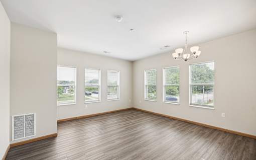 A large empty room with wooden floors and a chandelier.