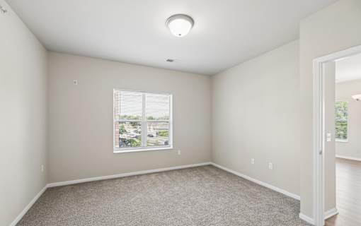 A room with a window and a carpeted floor.