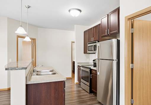A kitchen with a refrigerator, sink, and cabinets.