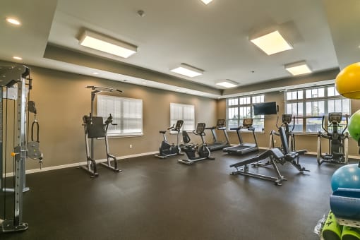a large fitness room with exercise equipment and windows
