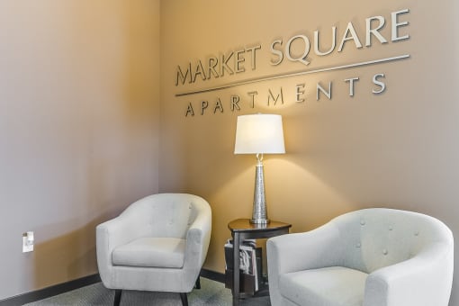two chairs and a lamp in a room with a sign that says market square apartments