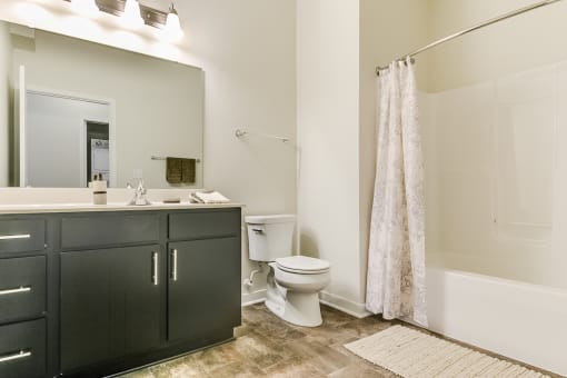 a bathroom with black cabinets and a white bathtub