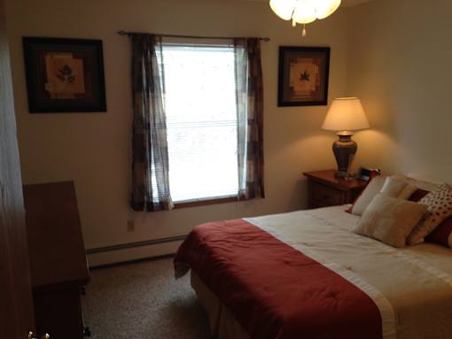A bedroom with a bed, nightstand, and window.