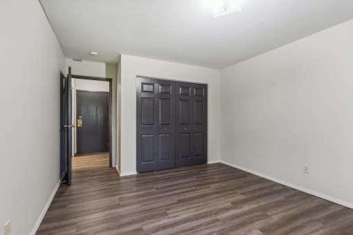 a empty room with a black door and wooden floors