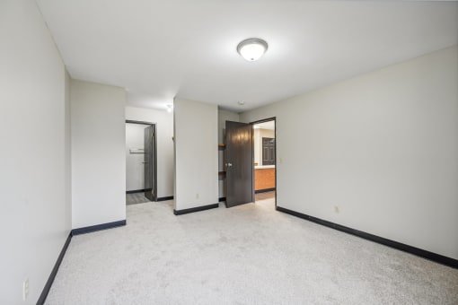 a empty living room with white walls and a door to a bathroom
