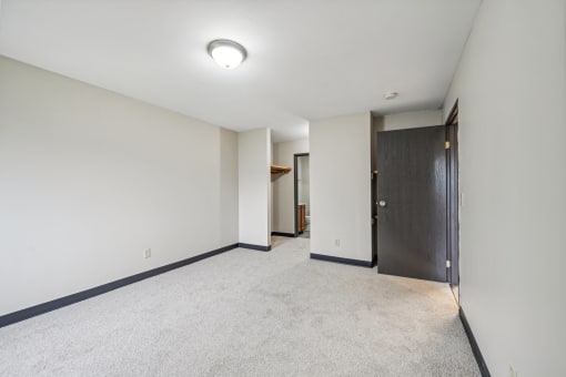 a living room with white walls and a door to a hallway