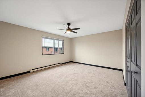 an empty living room with a ceiling fan and a window