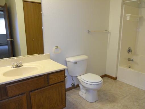 A white toilet sits in a bathroom next to a sink.