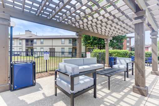 A patio with a table and chairs under a pergola.