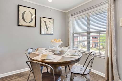 A dining table set with plates and napkins with a window behind it.