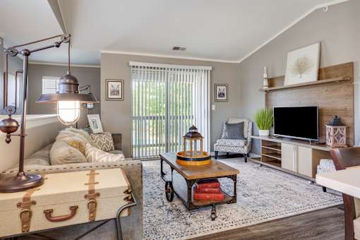 A living room with a couch, a chair, a coffee table, and a television.