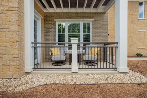 A patio with a table and chairs is surrounded by a white railing.