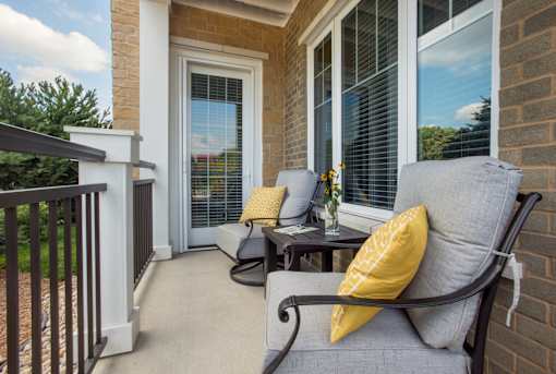 A patio with a black chair and a yellow pillow.