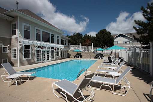 A pool with sun loungers and a building in the background.