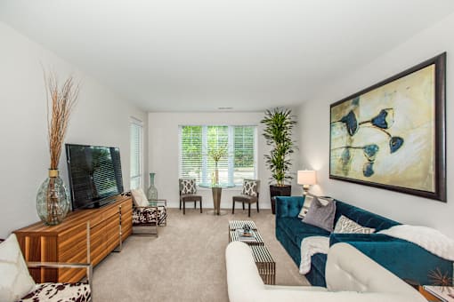 A living room with a white couch and a painting on the wall.