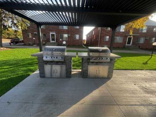 Two grills are on a patio in front of a building.