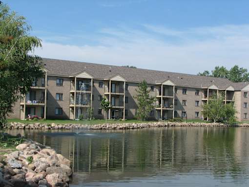 A building with a grey roof and a pond in front.