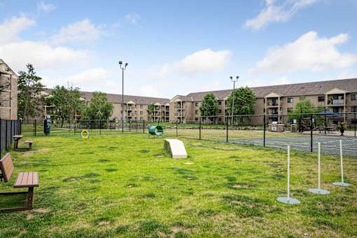 A playground area with a slide and a green ball in the middle of the grass.
