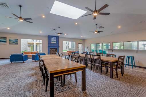 A large room with tables and chairs and a ceiling fan.