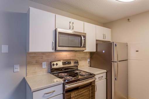 A kitchen with a stove, microwave, and refrigerator.