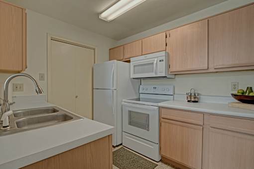 A kitchen with a sink, refrigerator, oven, and microwave.
