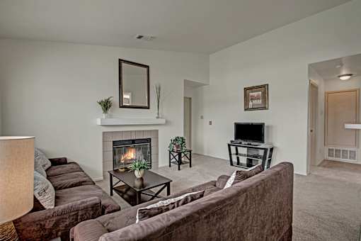 A living room with a fireplace and a brown couch.